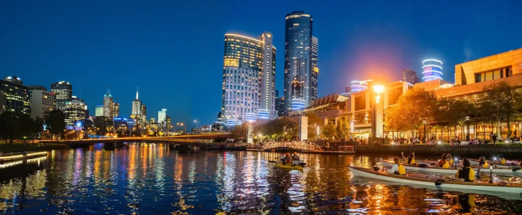 Kayakers paddling on the Yarra River at night with Melbourne city lights in the background